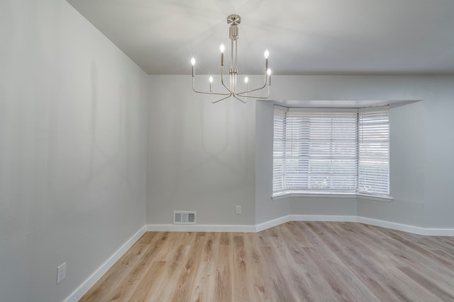 spare room with light hardwood / wood-style flooring and a chandelier