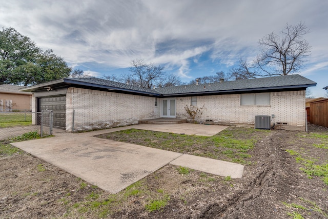 back of property with a garage, central AC, and a patio area