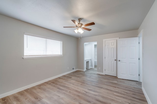 unfurnished bedroom featuring ensuite bath, light hardwood / wood-style floors, a closet, and ceiling fan