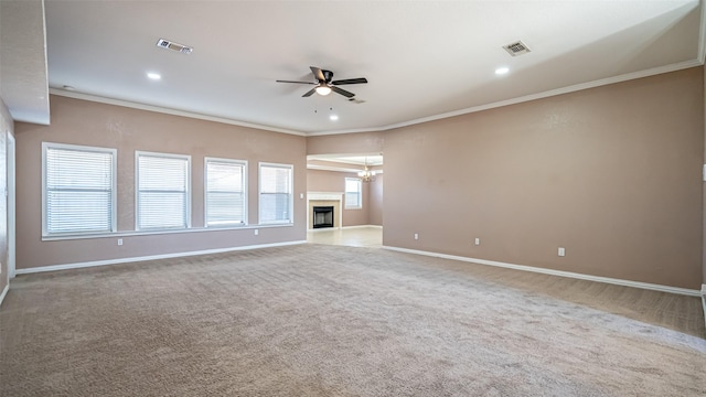 unfurnished living room featuring ceiling fan, ornamental molding, and carpet floors