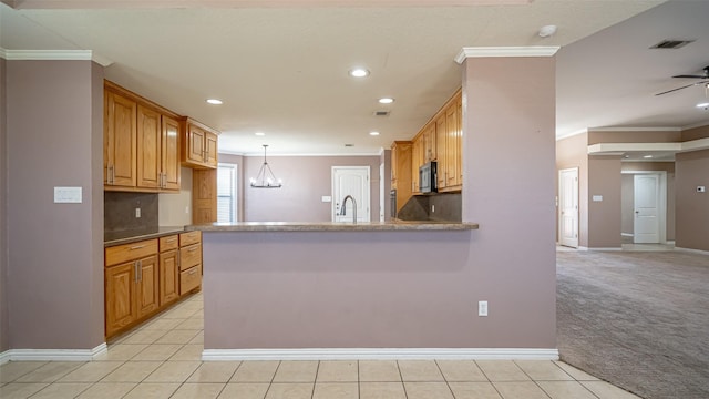 kitchen featuring crown molding, pendant lighting, light carpet, and kitchen peninsula