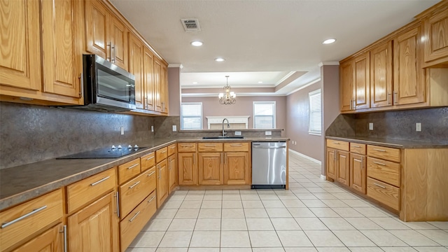 kitchen featuring appliances with stainless steel finishes, sink, hanging light fixtures, a tray ceiling, and crown molding