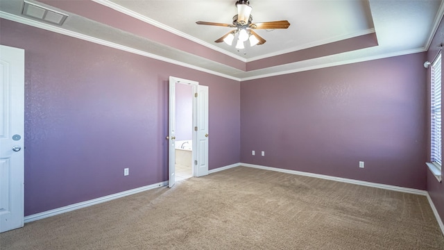 carpeted spare room with ceiling fan, ornamental molding, and a raised ceiling