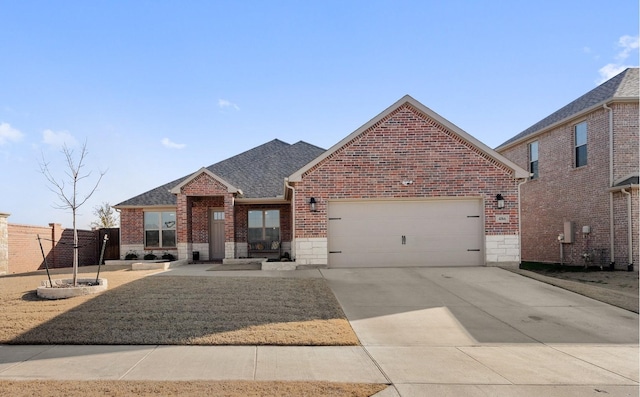 view of front of home featuring a garage, brick siding, stone siding, driveway, and roof with shingles