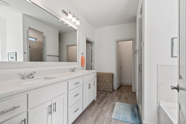 full bath with a sink, wood finished floors, a stall shower, and double vanity