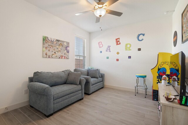 sitting room with baseboards, light wood-style floors, and ceiling fan