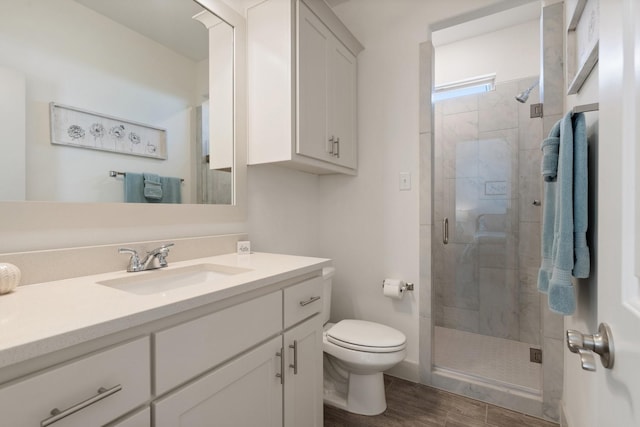 bathroom featuring wood finished floors, toilet, a stall shower, and vanity