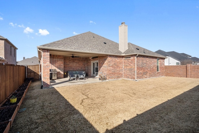 rear view of house with a ceiling fan, a patio area, brick siding, and a fenced backyard