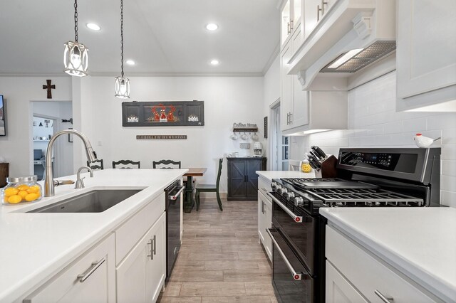 kitchen with sink, tasteful backsplash, black appliances, white cabinets, and a center island with sink