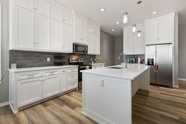 kitchen with sink, light hardwood / wood-style flooring, stainless steel appliances, an island with sink, and white cabinets