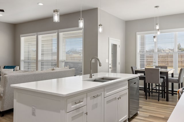 kitchen featuring white cabinetry, decorative light fixtures, sink, and a center island with sink