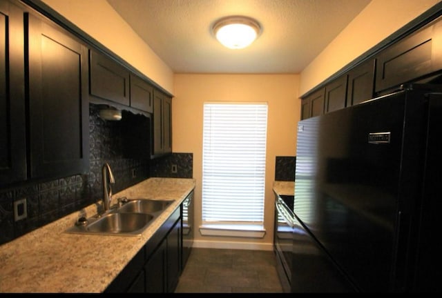 kitchen with dark brown cabinetry, sink, black refrigerator, light stone countertops, and backsplash