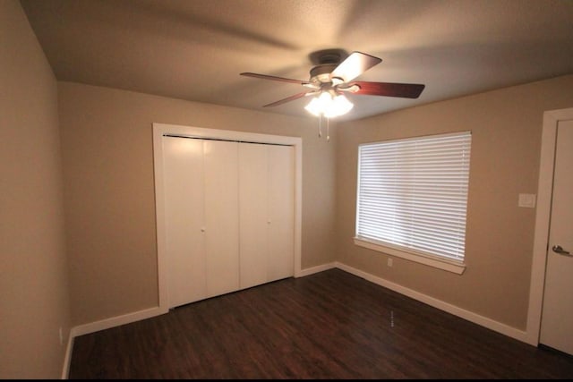 unfurnished bedroom featuring dark wood-type flooring, ceiling fan, and a closet