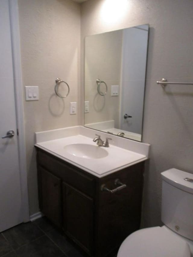 bathroom featuring vanity, tile patterned floors, and toilet