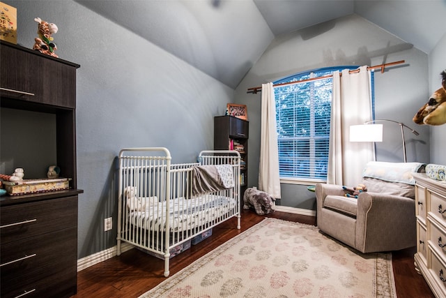 bedroom with a nursery area, lofted ceiling, and hardwood / wood-style flooring