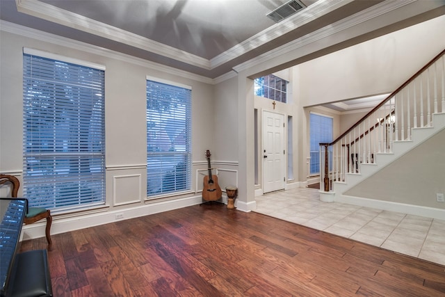 foyer featuring hardwood / wood-style flooring, ornamental molding, and a tray ceiling