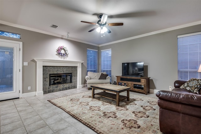 tiled living room featuring a tiled fireplace, ornamental molding, and ceiling fan