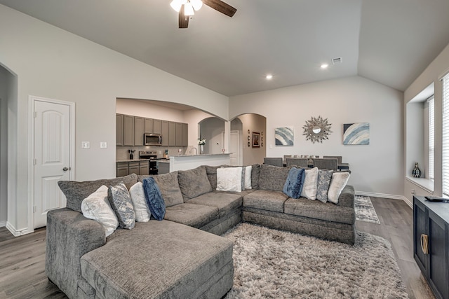 living room with lofted ceiling, hardwood / wood-style flooring, and ceiling fan