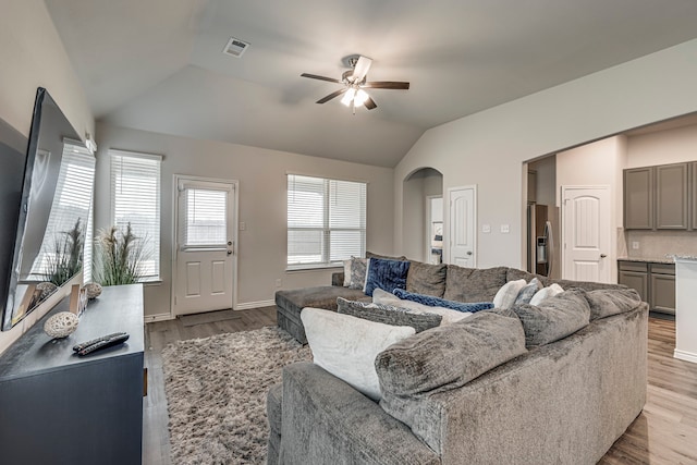 living room with ceiling fan, light hardwood / wood-style floors, and vaulted ceiling