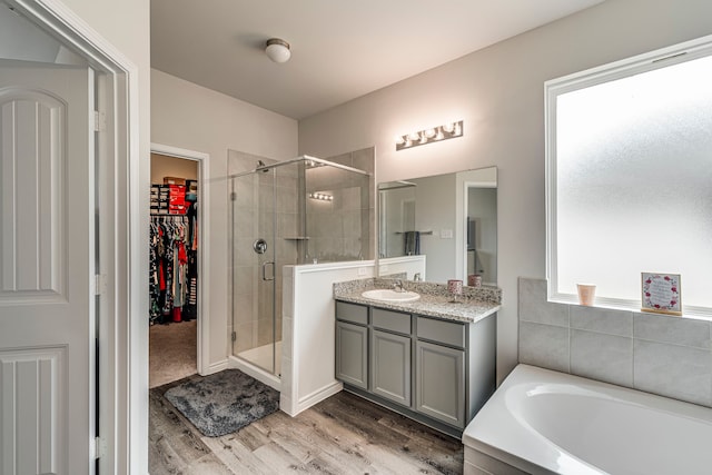 bathroom with wood-type flooring, separate shower and tub, and vanity