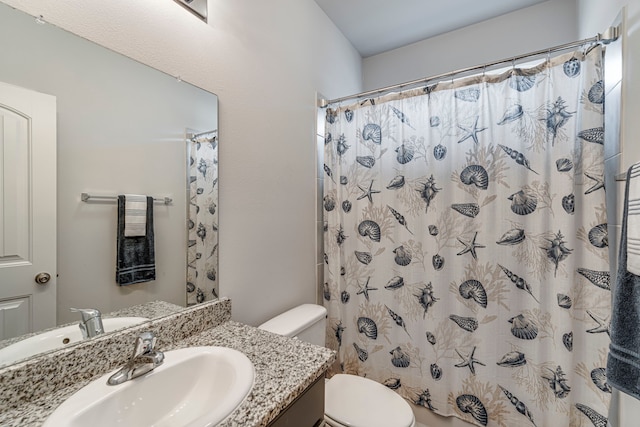 bathroom with walk in shower, vanity, and toilet