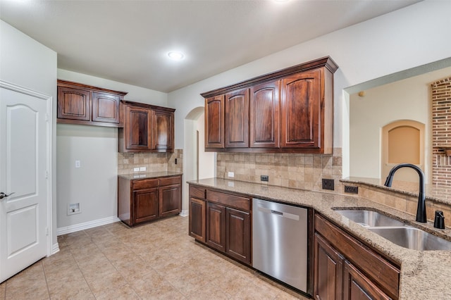 kitchen with tasteful backsplash, light stone countertops, sink, and stainless steel dishwasher