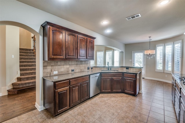 kitchen with sink, hanging light fixtures, backsplash, stainless steel dishwasher, and kitchen peninsula