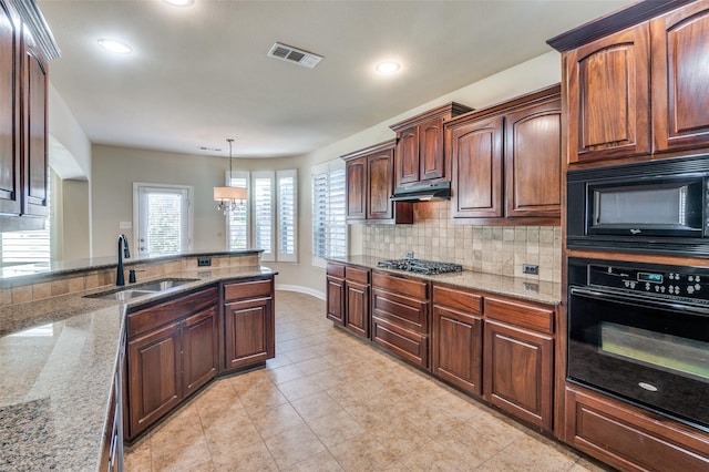 kitchen with sink, backsplash, hanging light fixtures, black appliances, and light stone countertops