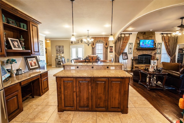 kitchen with light tile patterned flooring, a center island, a fireplace, and decorative light fixtures