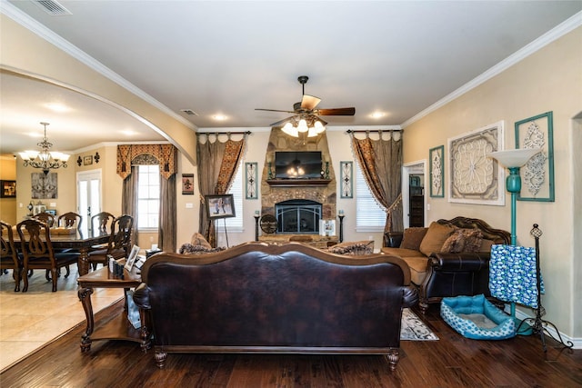 living room with hardwood / wood-style flooring, a fireplace, ornamental molding, and ceiling fan with notable chandelier