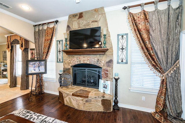 living room featuring crown molding, a stone fireplace, and hardwood / wood-style flooring