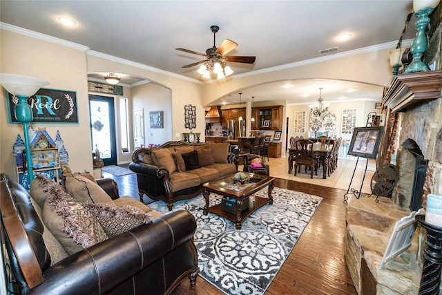 living room with hardwood / wood-style flooring, crown molding, and ceiling fan with notable chandelier