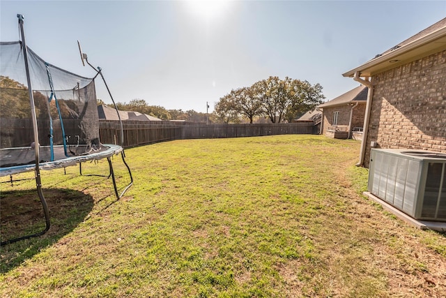 view of yard with a trampoline and central air condition unit