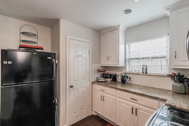 kitchen with black refrigerator, backsplash, white cabinets, and dark hardwood / wood-style flooring