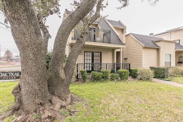 view of front of house with a front lawn and a balcony