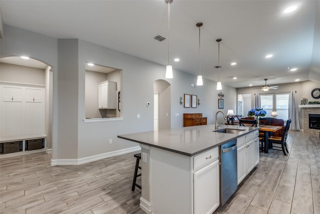 kitchen with pendant lighting, sink, dishwasher, an island with sink, and white cabinets