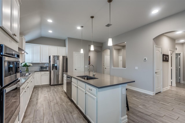 kitchen with sink, white cabinetry, stainless steel appliances, an island with sink, and decorative light fixtures