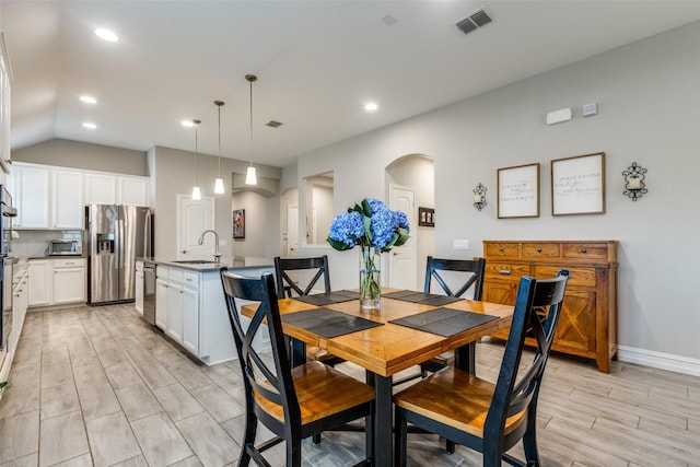 dining room featuring lofted ceiling and sink