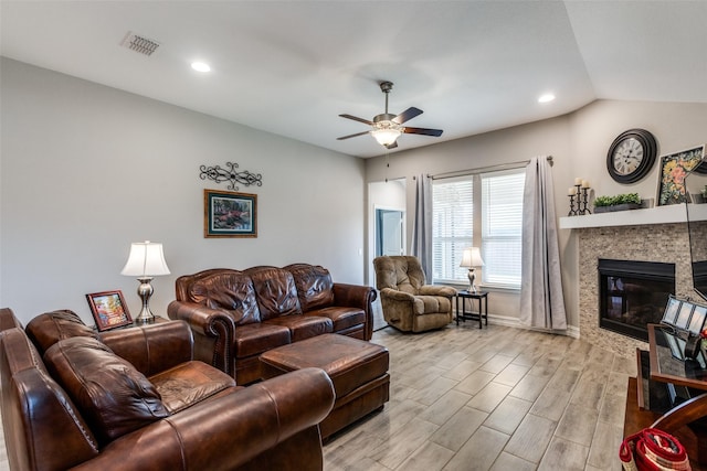 living room featuring a tile fireplace, vaulted ceiling, ceiling fan, and light hardwood / wood-style floors