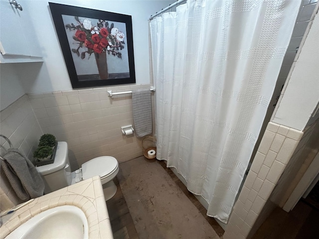 bathroom featuring walk in shower, toilet, sink, and tile walls