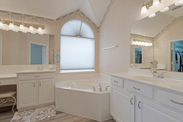 bathroom with lofted ceiling, a bath, vanity, and hardwood / wood-style floors