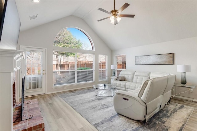 living room with ceiling fan, high vaulted ceiling, and light hardwood / wood-style floors