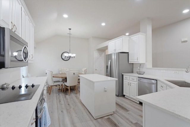 kitchen featuring appliances with stainless steel finishes, decorative light fixtures, white cabinetry, sink, and a center island