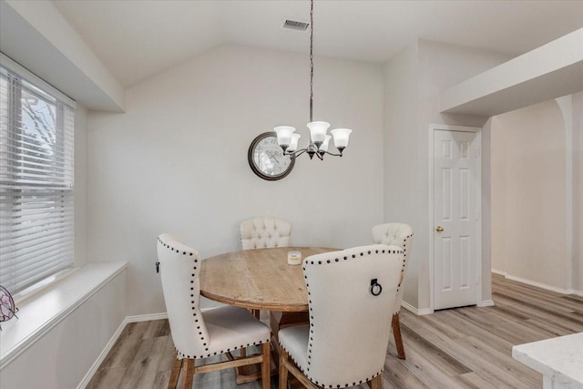 dining area with light hardwood / wood-style floors, vaulted ceiling, and a notable chandelier