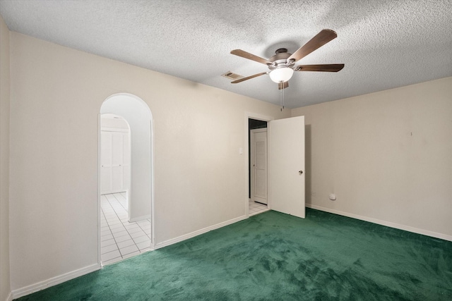 carpeted empty room with ceiling fan and a textured ceiling