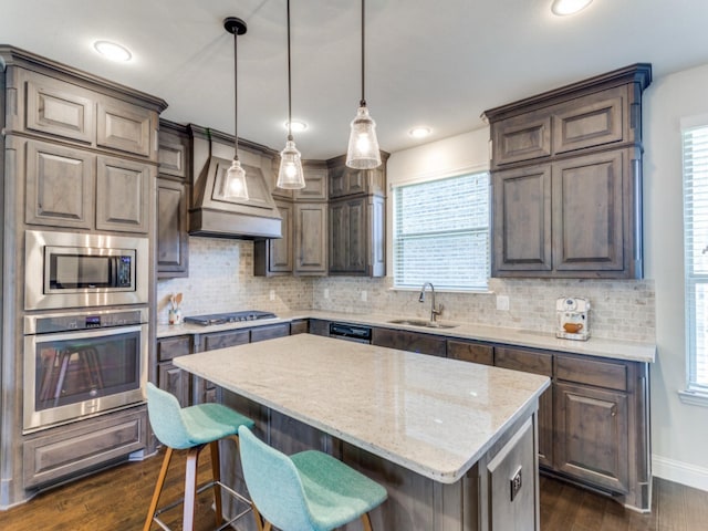 kitchen with sink, light stone counters, a center island, dark hardwood / wood-style flooring, and stainless steel appliances