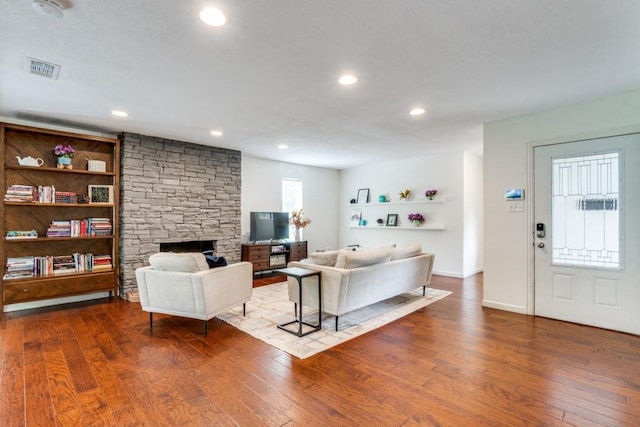 living room with hardwood / wood-style floors, built in shelves, and a fireplace