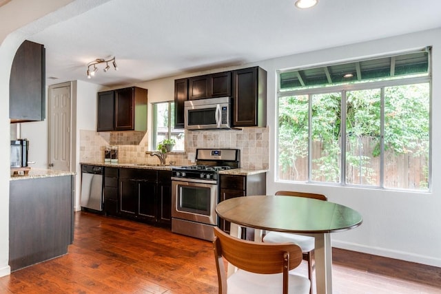 kitchen featuring sink, tasteful backsplash, dark hardwood / wood-style flooring, stainless steel appliances, and light stone countertops