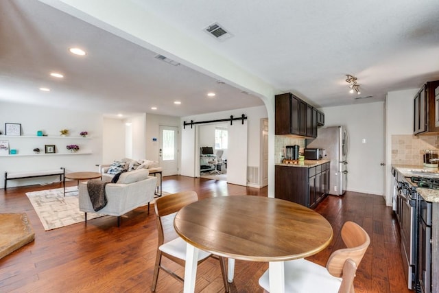 dining room with dark wood-type flooring and a barn door