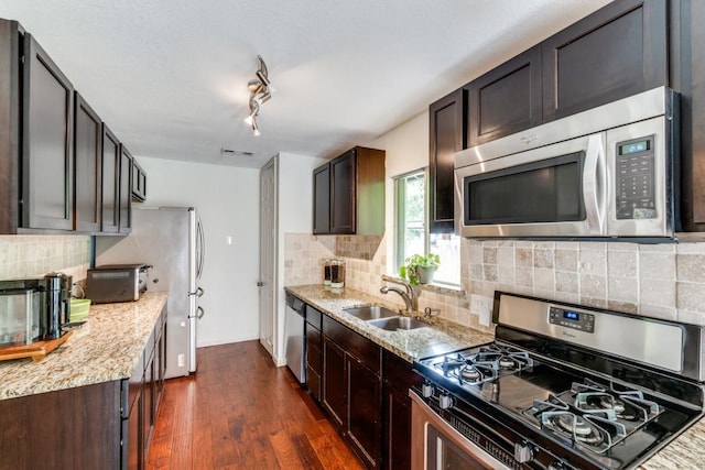 kitchen with dark hardwood / wood-style floors, sink, light stone counters, stainless steel appliances, and dark brown cabinets